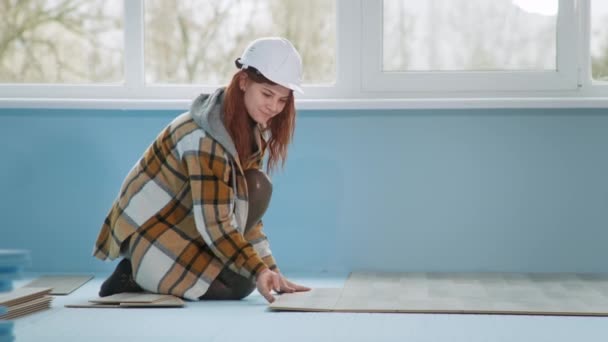 Bauarbeiterin mit Helm legt bei Renovierung Laminat auf mit Polyesterschaum isoliertem Boden in Wohnung - Filmmaterial, Video