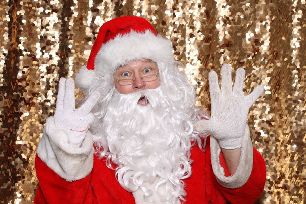 Santa Claus. Santa Claus holds Eight Fingers in the air as he says there are ONLY 8 Days Until Christmas. Gold Sequin Background. Christmas Holiday Images. - Φωτογραφία, εικόνα