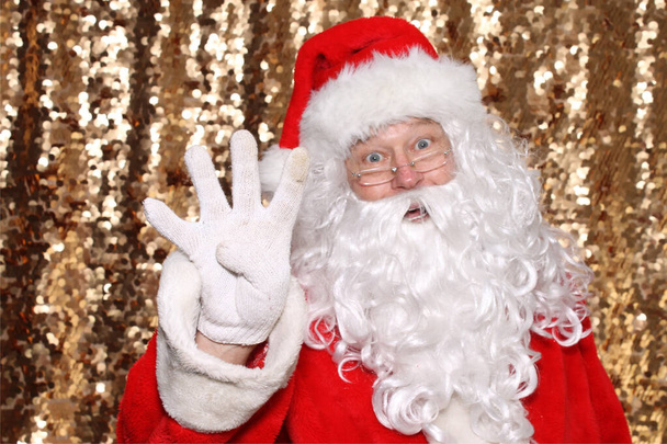 Santa Claus. Santa Claus holds Four Fingers in the air as he says there are ONLY 4 Days Until Christmas. Gold Sequin Background. Christmas Holiday Images. - Φωτογραφία, εικόνα