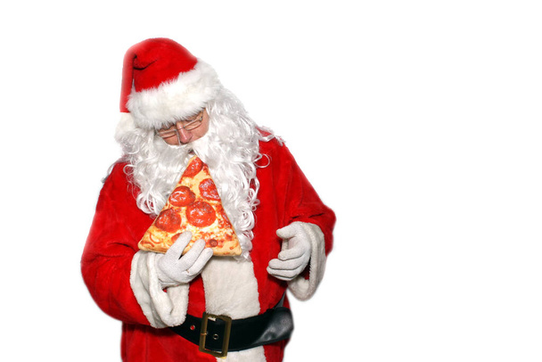 Santa Claus. Isolated on white. Room for text. Santa Claus enjoys and Eats a Slice of Pepperoni Pizza. - Fotoğraf, Görsel