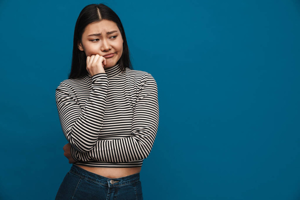 Displeased asian teen girl posing and looking aside isolated over blue background - Foto, immagini