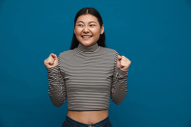 Excited asian teen girl gesturing and laughing at camera isolated over blue background - Fotoğraf, Görsel