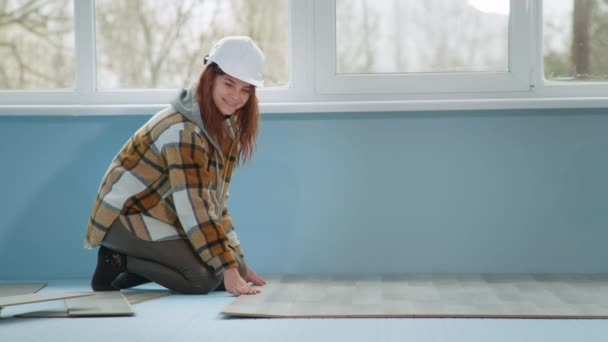 Frau mit Schutzhelm legt bei Renovierung in Wohnung Laminat auf Boden - Filmmaterial, Video