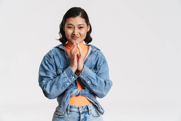Happy smiling young asian brunette woman in denim jacket posing standing over gray background - Фото, зображення