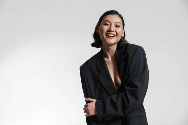 Young white asian woman in jacket standing posing over white wall background looking at camera arms folded - Foto, immagini
