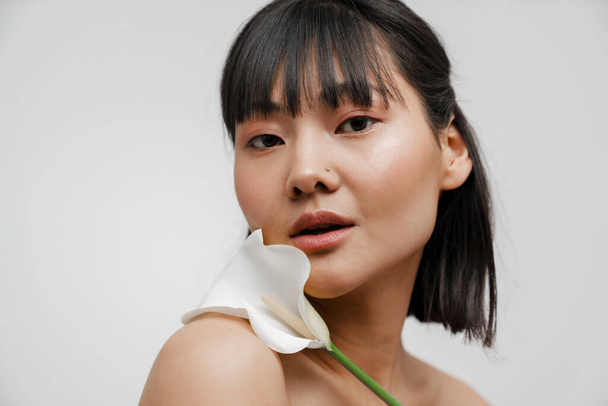 Young asian shirtless woman with piercing posing wit flower isolated over white background - Photo, image