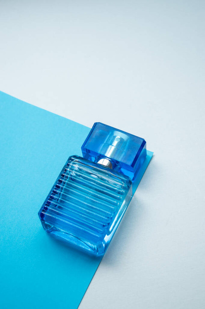 Mała niebieska szklana butelka zapachowa na niebiesko-białym tle z przestrzenią do kopiowania  - Zdjęcie, obraz