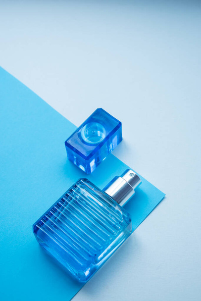 Kleine blauwe glazen geurfles op een blauw-witte achtergrond met kopieerruimte  - Foto, afbeelding