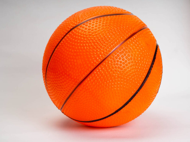 Φωτογραφία από ένα πορτοκαλί καλάθι μπάλα σε ένα δαχτυλίδι καλάθι. Πυροβολήστε σε λευκό φόντο - Φωτογραφία, εικόνα