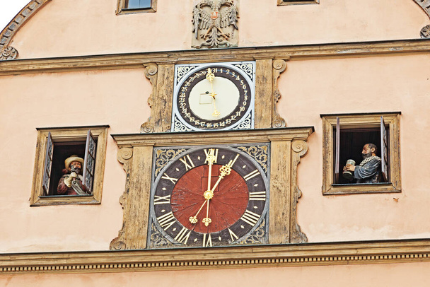 В немецком городе Ротенбург-об-дер-Таубер стоит колокольня часов каждый час и две двери открываются по обе стороны часов, чтобы воссоздать легендарную историю храброго мэра, который выпил почти галлон вина, чтобы спасти свой город - Фото, изображение
