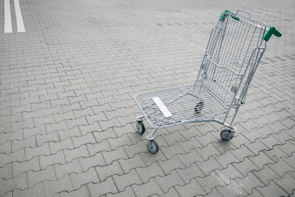 Trolley winkelen. Lege winkelwagentje bij supermarkt parkeerplaats. Tijd om huishoudelijke artikelen, snacks of bouwmaterialen te kopen - Foto, afbeelding