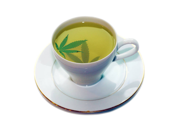Травяной чай каннабиса в чашке чая с зелеными листьями марихуаны. Медицинские цели для сна и тревоги. Концепция чая с марихуаной и здоровых напитков. Травяной чай с марихуаной. Медицинский чай с марихуаной. Чай с марихуаной.  - Фото, изображение