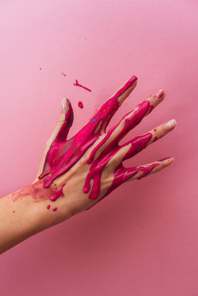 Hand in pink paint on a pink background. Gentle manicure. Female hand. - Fotó, kép