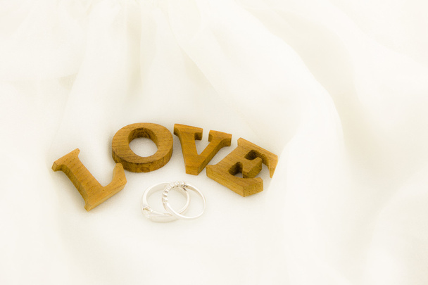 liefde formulering en ringen op zachte witte jurk - Foto, afbeelding