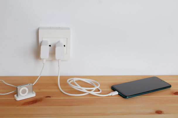 Подключите розетку питания Зарядное устройство шнура адаптера смартфона и mp3 плееров, гаджетов, на деревянном полу - Фото, изображение