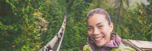 Canada travel tourist woman taking selfie photo at Capilano Suspension Bridge in Vancouver, British Columbia, canadian vacation destination for tourist. Asian girl talking to camera phone. - Foto, afbeelding