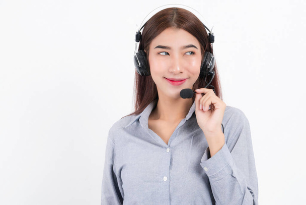 Porträt einer glücklich lächelnden Telefonistin mit kurzen Haaren, die ein weißes Hemd mit einem Kopfhörer trägt, der seitlich steht und den Kopfhörer isoliert auf weißem Hintergrund hält. - Foto, Bild