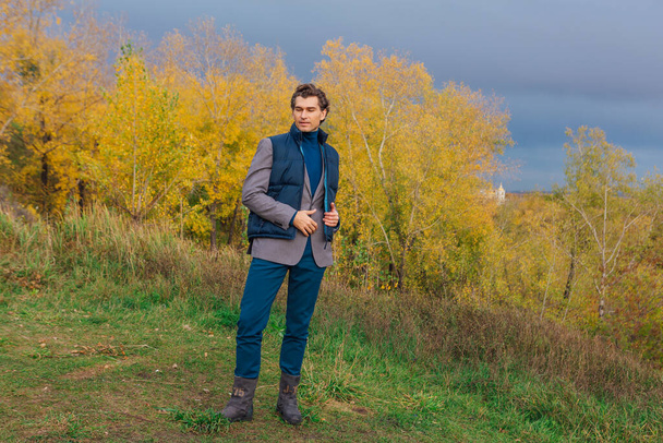 Tall handsome man walking outdoor in yellow autumn forest on the hill before storm - Fotoğraf, Görsel