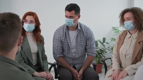 training tijdens een pandemie, jonge vrouw met medisch masker ter bescherming tegen virus en infectie deelt psychologische en emotionele ervaringen tijdens groepstherapie in vertrouwenscirkel - Video