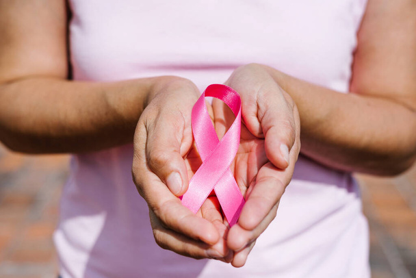 mãos de mulher segurando fitas de consciência de câncer de mama rosa com céu azul como pano de fundo na América Latina - Foto, Imagem