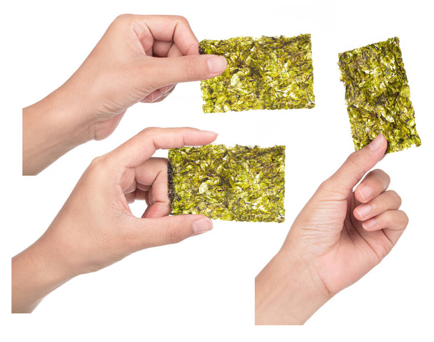 Σύνολο του χεριού κρατώντας Crispy Nori Seaweed απομονώνονται σε λευκό φόντο. - Φωτογραφία, εικόνα