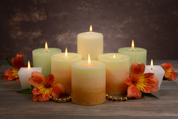 Beautiful candles with flowers on table on brown background - Foto, Imagem