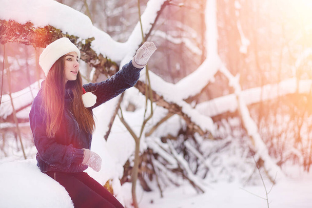 A young girl in a winter park on a walk. Christmas holidays in the winter forest. Girl enjoys winter in the park - Foto, Imagen