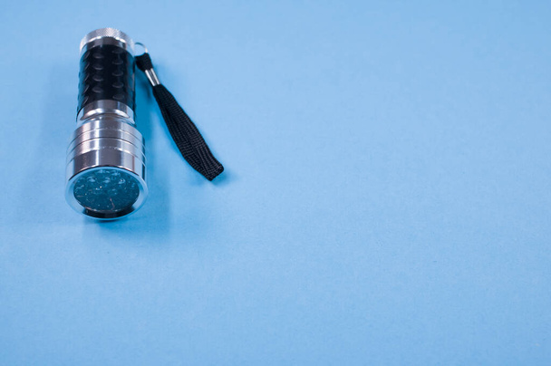 mini led flashlight on a blue color surface with text space - Φωτογραφία, εικόνα