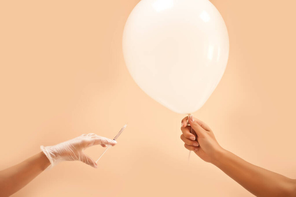 Concept with syringe and hand in gloves injecting a balloon. Spa, medicine, healthcare, treatment, beauty concept - Foto, immagini