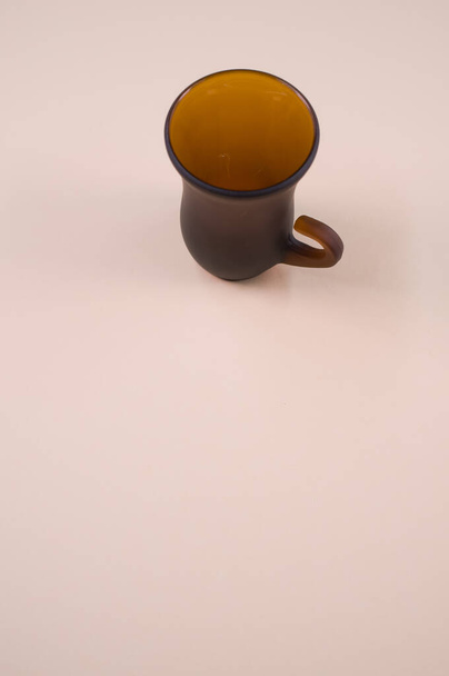 A closeup of a brown teacup on the beige-colored surface - Fotó, kép