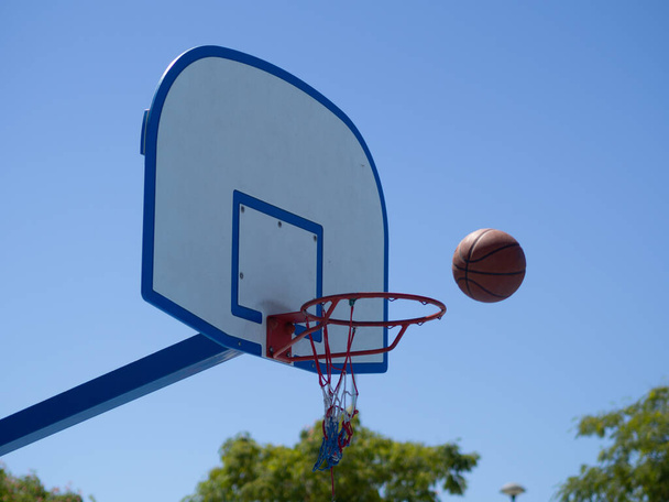 A low angle shot of a basketball ball falling into the hoop - Foto, Imagen