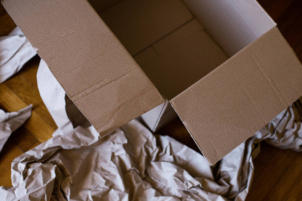 Вид сверху на пустую коробку и коричневую оберточную бумагу на полу - Фото, изображение
