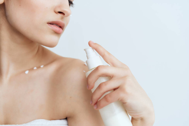 woman with bare shoulders applies lotion to body  - Foto, Bild