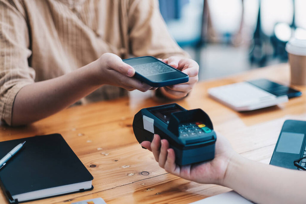 A woan using her mobile to made a payment wireless with EDC machine or credit card terminal. Mobile payment concept with virtual credit card - Foto, Imagem