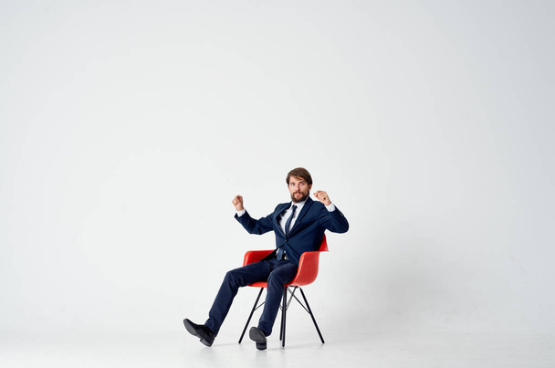 Hombre alegre sentado en la silla roja  - Foto, imagen