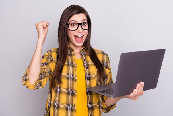 Photo of young excited woman happy positive smile rejoice victory success hold laptop isolated over grey color background - Foto, Imagem