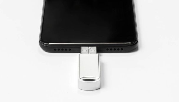Φορητό USB flash drive συνδεδεμένο στο κινητό τηλέφωνο απομονώνονται σε λευκό φόντο. Κοπάδι. - Φωτογραφία, εικόνα