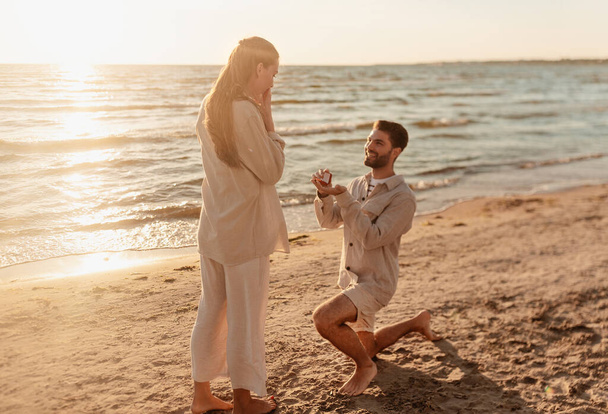 man with ring making proposal to woman on beach - Foto, Bild