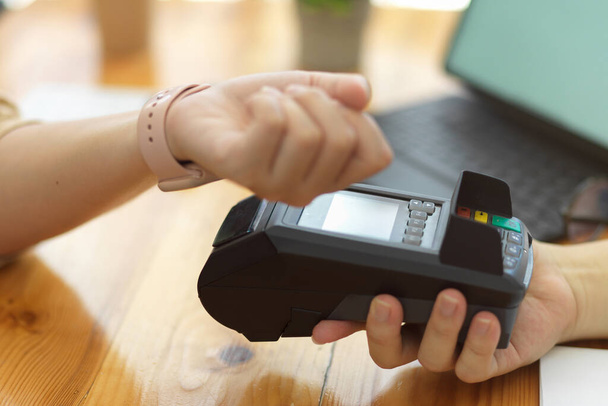NFC-tekniikka, Nainen maksaa digitaalisella lompakkopalvelulla älykellon kautta maksupäätteellä  - Valokuva, kuva