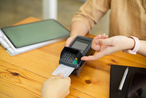Klant die met credit card betaalt, credit card in betaalautomaat invoegen, POS terminal - Foto, afbeelding