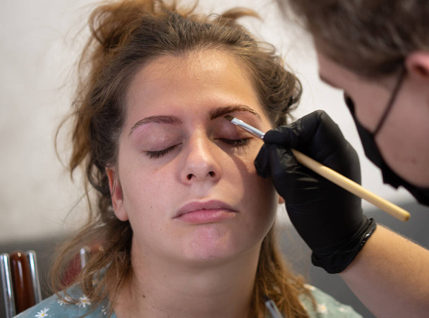 Maquillaje esteticista aplica pintura de henna a las cejas. Cuidado facial profesional. - Foto, Imagen