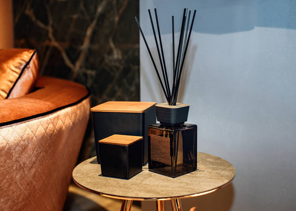 Reed difusor e caixas decorativas sobre a mesa elegante no interior da casa de estilo contemporâneo. Frasco de fragrância em casa com varas de vime. - Foto, Imagem