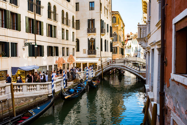 ヴェネツィア- 2021年8月:人々はヴェネツィアの都市の運河の一つに沿って歩く. - 写真・画像