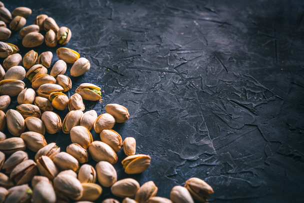 Pistachios scattered on a dark table, with copy space. Ready to eat nuts. Energy food.  - Foto, Imagem