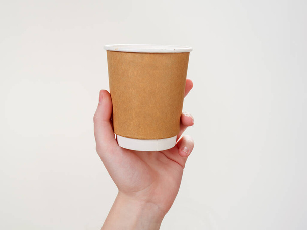 使い捨てコーヒーペーパー白の背景に孤立した手で環境に優しいカップ2021 - 写真・画像