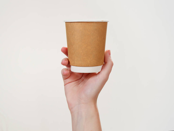 wegwerp koffie papier eco-vriendelijke beker in de hand geïsoleerd op witte achtergrond 2021 - Foto, afbeelding