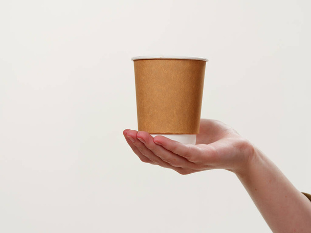 одноразовые кофе бумага экологически чистая чашка в руке изолированы на белом фоне 2021 - Фото, изображение