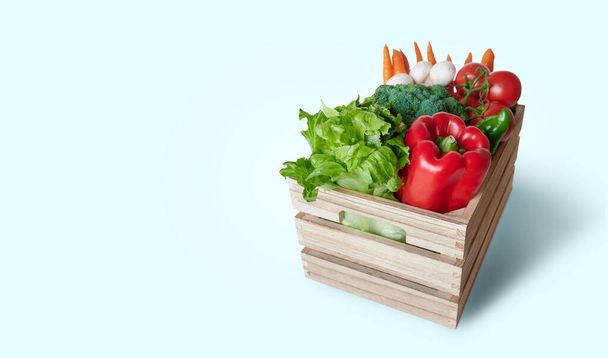 Verdure fresche in scatola di legno isolata su sfondo blu con copia dello spazio - Foto, immagini