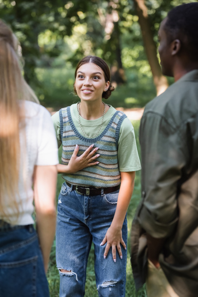 Счастливая девочка-подросток разговаривает с межрасовыми друзьями на открытом воздухе  - Фото, изображение