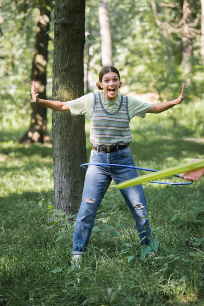 Aufgeregt Teenager Mädchen drehen Hula-Hoop-Reifen auf Gras in Park  - Foto, Bild